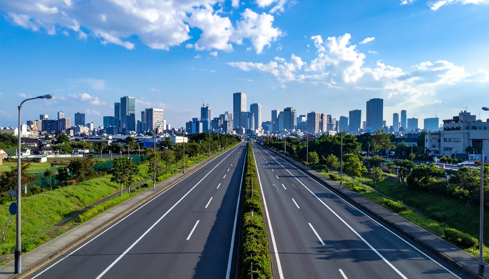 都市へ向かって延びる道路と青空